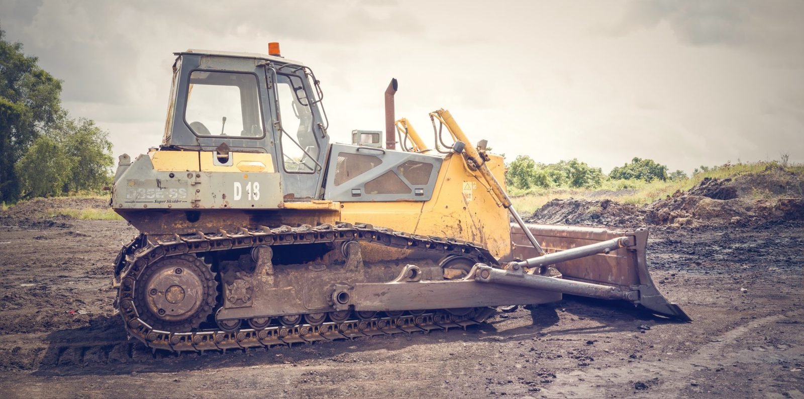Crawler dozer with its blade down on a muddy graded site