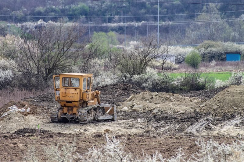Bulldozer among brush and churned ground on a rural lot