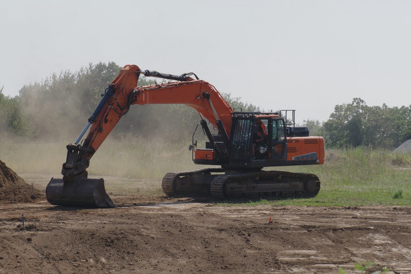 Excavator dragging its bucket to level a dirt site